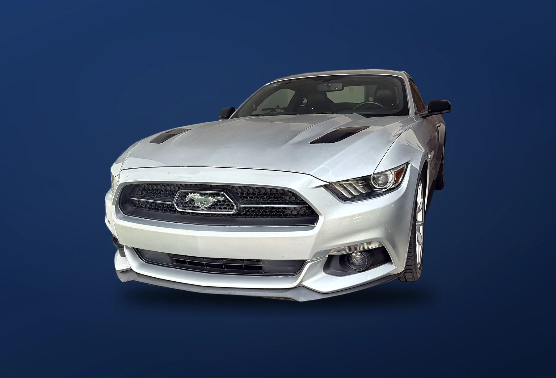 Mustang plateado de frente a tres cuartos sobre fondo azul DROASA; vehículo ilustrativo para piezas usadas